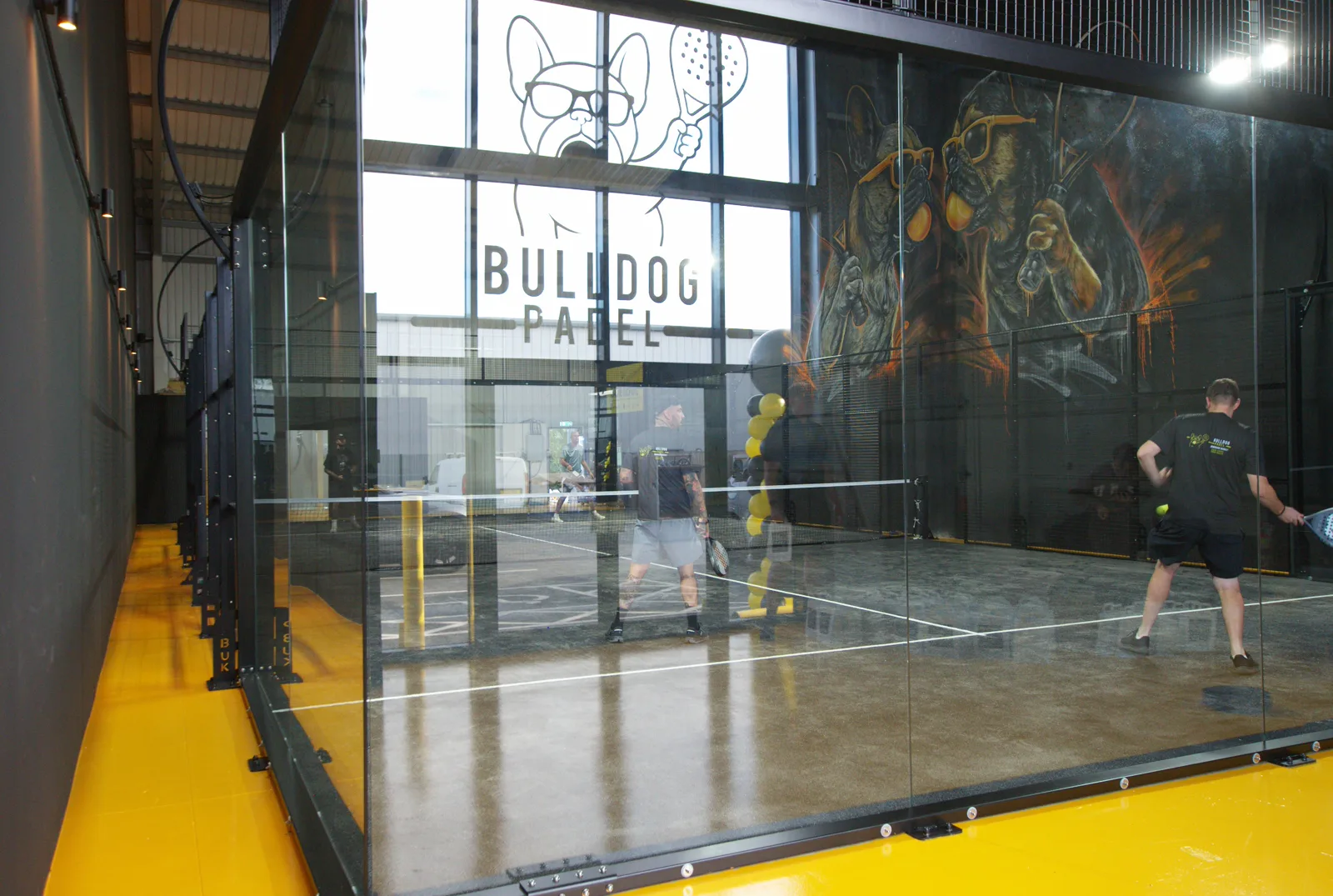Players on the private indoor court beneath the Bulldog Padel mural